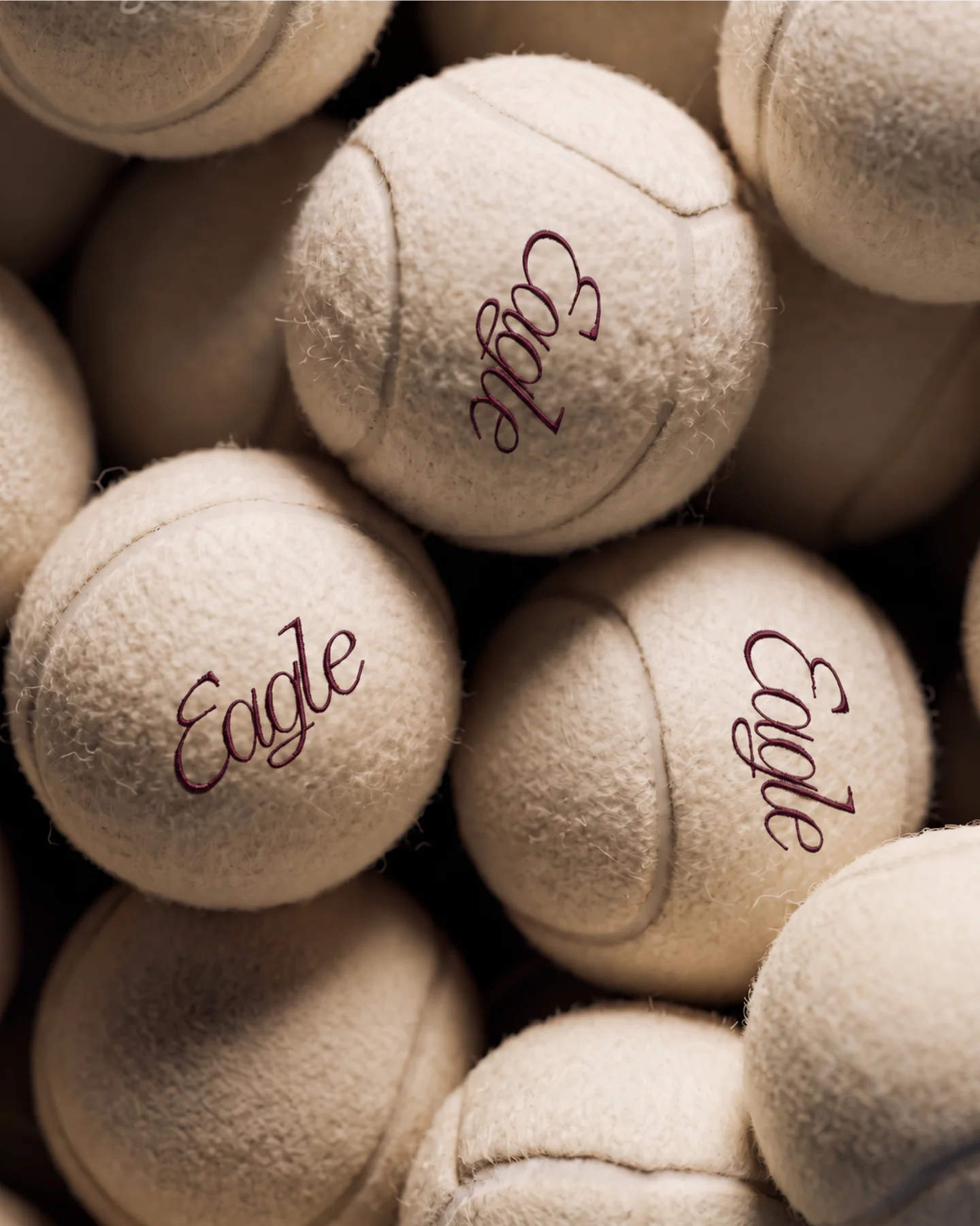 A pile of cream tennis balls printed with the Eagle wordmark.