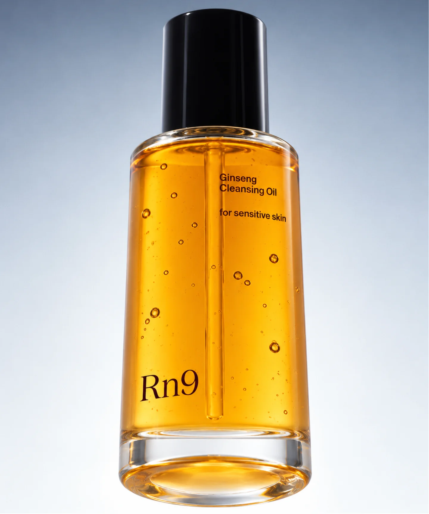 Amber Rn9 cleansing oil bottle photographed against a cool grey background.