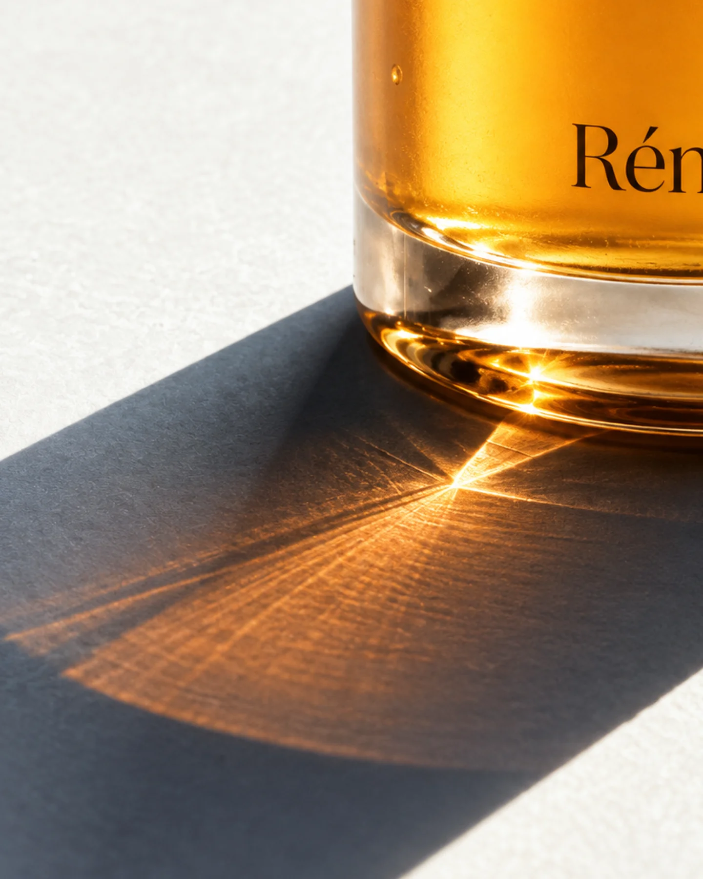 Amber Réneuf bottle casting a warm, patterned shadow.