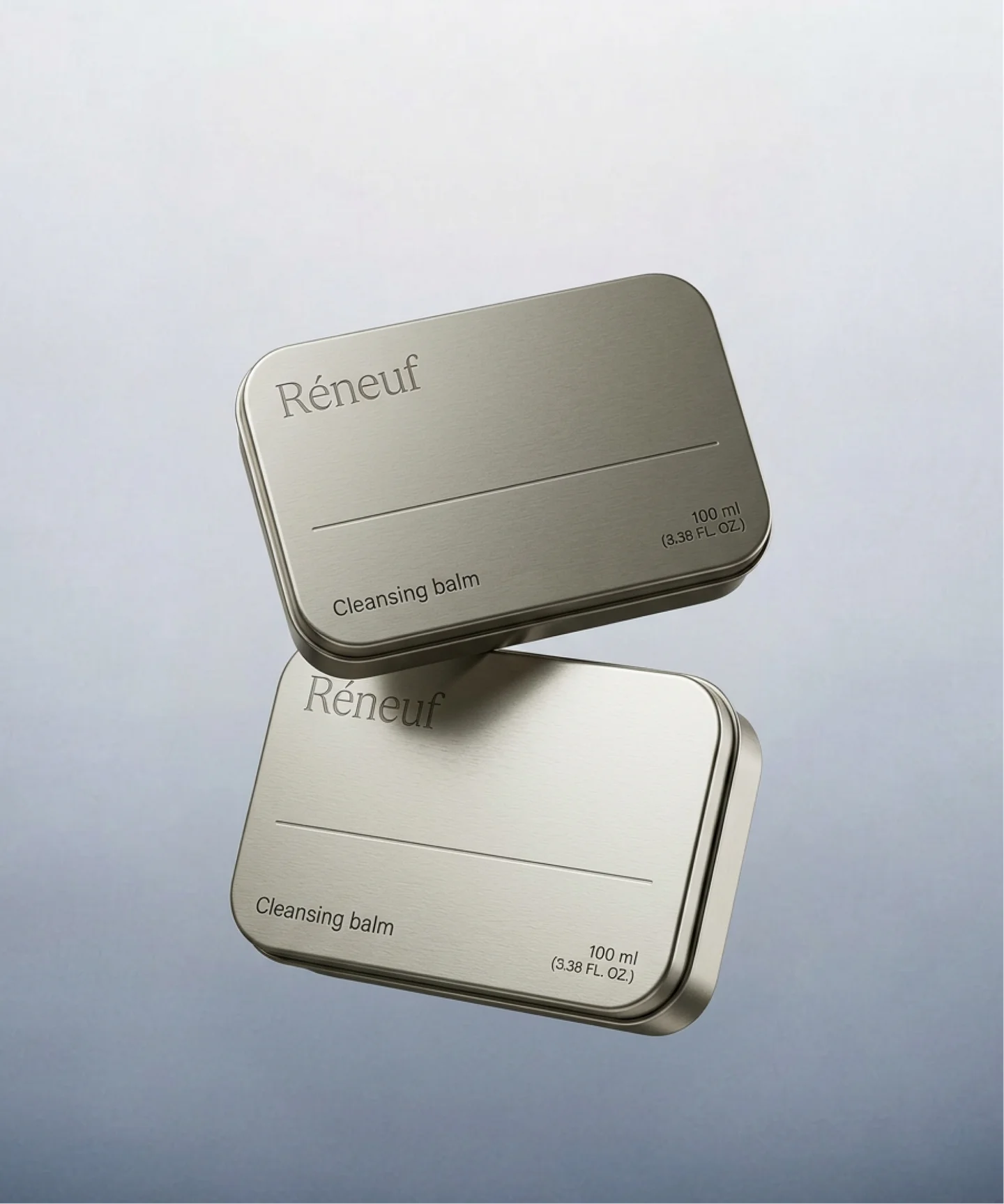 Two silver Réneuf cleansing balm tins stacked at an angle.